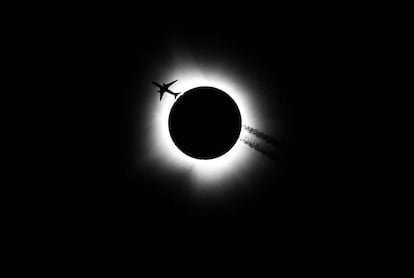 Un avión cruza frente al sol durante el eclipse solar, visto desde Bloomington (Estado de Indiana, EE UU).