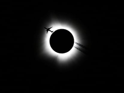 Un avión cruza frente al sol durante el eclipse solar, visto desde Bloomington (Estado de Indiana, EE UU).