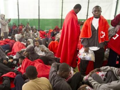 Los inmigrantes esperan pasar a disposici&oacute;n de las autoridades tras ser atendidos en un polideportivo de Tarifa.
