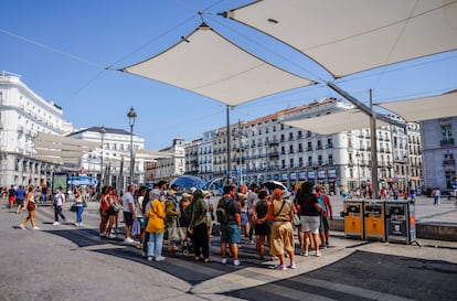 Varias personas esperan a la sombra de los toldos de Puerta del Sol, este lunes en Madrid.