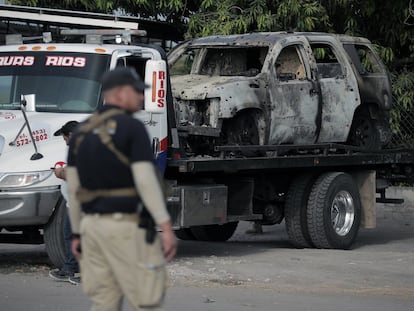 Una grúa retira el vehículo calcinado y baleado en el que fue asesinado Hipólito Mora, el 29 de junio en La Ruana (Michoacán).