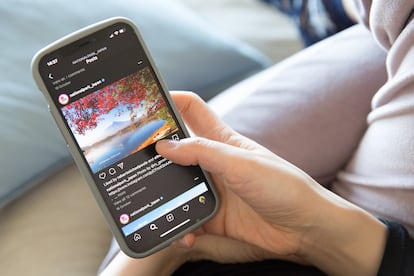 Una mujer sostiene un iPhone 12 mientras revisa el feed de Instagram.
