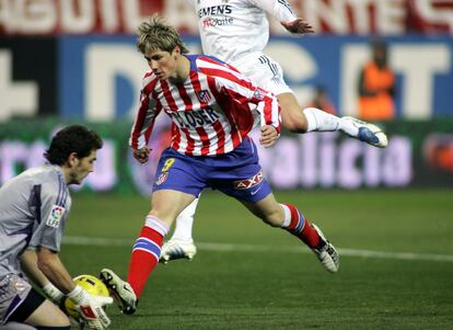 El portero del Real Madrid, Íker Casillas (primer plano), para un balón en presencia del jugador del Atlético de Madrid, Fernando Torres (c)  durante el partido de Primera División de Fútbol entre el Atlético de Madrid - Real Madrid, el 9 de enero de 2005.