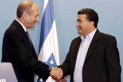 El primer ministro israelí, Ehud Olmert (izda.), estrecha la mano del presidente del partido Laborista, Amir Peretz.