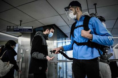 Un empleado de metro distribuye gel hidroalcohólico a los viajeros antes de salir de suburbano de París.