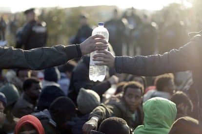 Dos migrantes comparten una botella de agua mientras esperan a ser registrados en 'La Jungla' de Calais. 