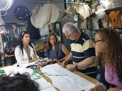 El maestro de costura Hugo Herrera (centro) acompañado de varias de sus estudiantes en el taller de costura. en Nueva York.