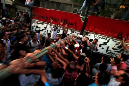 Los manifestantes emplean un palo de hierro para derribar el muro construido al rededor de la embajada de Israel en El Cairo ayer por la tarde.