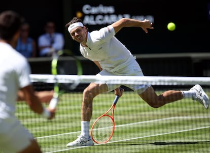 Taylor Fritz (al fondo) pega la pelota ante Carlos Alcaraz.