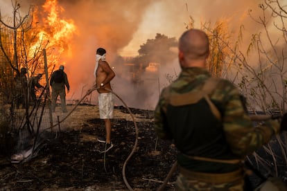 Voluntarios utilizan mangueras en el incendio en Ano Patima, al norte de Atenas, el lunes.