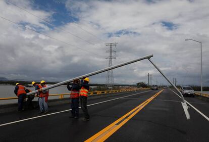 Unos trabajadores en el momento de levantar un poste de luz que cayó sobre una autopista en el Estado de Sinaloa.