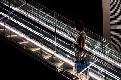 Una mujer protegida con una mascarilla, sube por unas escaleras mecánicas de un centro comercial en Tokio (Japón).