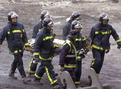 Los bomberos trasladan el cadáver de Diego Armando Estacio tras recuperarlo de los escombros.