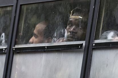 Varios migrantes sudaneses y eritreos miran por las ventanillas de un autobús durante el desalojo de un campamento temporal de inmigrantes, en la avenida Flandre en el norte de París (Francia).