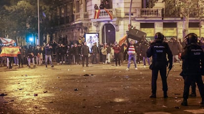 Un hombre coge un contenedor frente a la policía en la confluencia entre las calles de Marqués de Urquijo y Ferraz, este martes. / CLAUDIO ÁLVAREZ