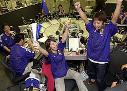 Empleados de la Bolsa de Tokio, vestidos con la camiseta de su selección, se alborozan por el triunfo sobre Túnez.