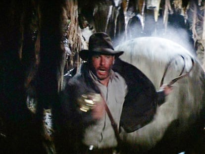 Imagen de 'En busca del arca perdida', en la que Indiana Jones, con su sombrero y látigo, corre para no ser aplastado por una gran bola de piedra.