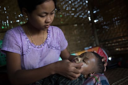 La esposa de un empleado de la industria del petróleo aplica a un bebé thanaka, una pasta hecha a base de sándalo, el pasado 11 de agosto de 2015 en Minhla, Myanmar. Esta localidad ha desarrollado desde 2006 una gran actividad petrolera y, aunque la producción ha decaido en los últimos cuatro meses, campesinos de toda la región siguen buscando empleo en los pozos con la esperanza de ganar más que como agricultores.