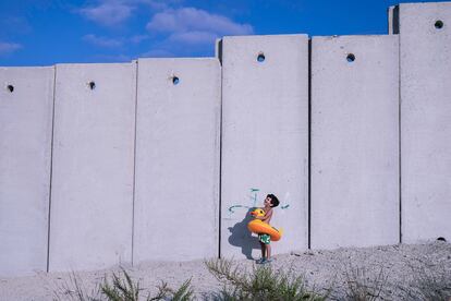 En esta exposición, fuera de concurso y en el marco del proyecto 'Somos Constructores' de l’Associació Catalana per la Pau, dos fotógrafas y un fotógrafo de Palestina, y uno español muestran el sufrimiento del pueblo palestino, pero también su resistencia y capacidad de supervivencia ante la ocupación israelí. En la imagen, un niño palestino al lado del muro del 'apartheid' israelí. La mayoría de la infancia que vive en Cisjordania bajo la ocupación israelí no tiene acceso al mar. Los que desean ir han de solicitar permisos especiales que casi siempre son rechazados.