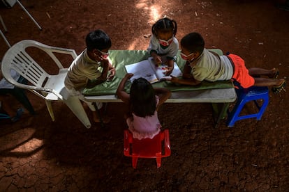 Un grupo de niños indígenas emberá consulta un libro durante una clase, en marzo de 2021, en Puru Embera, provincia de Colon, Panamá. En tiempos de pandemia y sin conexión a internet, estudiantes como ellos reciben lecciones gracias a profesores que se desplazan largas distancias hasta sus comunidades.