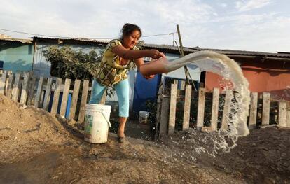 Una mujer arroja agua sucia afuera de su casa en Callao, Perú