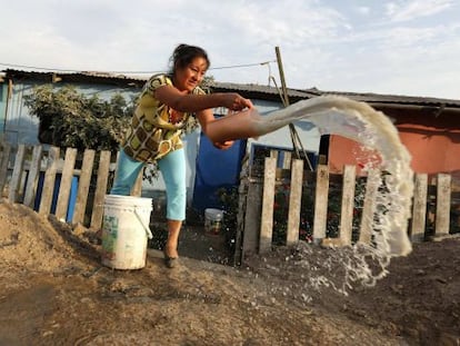 Una mujer arroja agua sucia afuera de su casa en Callao, Per&uacute;