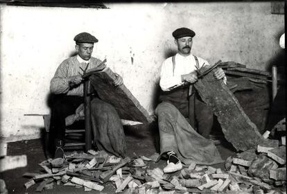 Dos hombres cortando panas de corcho con gavineta y guía, para sacar trozas para tapones (años 20). El autor de la foto fue Jaume Ferrer y procede del archivo del Museu del Suro de Pallafrugell.