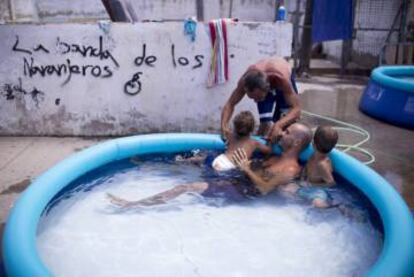 Varios vecinos se refrescan en una piscina hinchable.