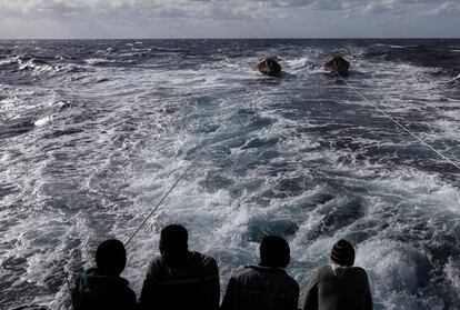 Varios migrantes rescatados observan el mar desde la popa del antiguo pesquero Golfo Azzuro, en el Mar Mediterráneo.