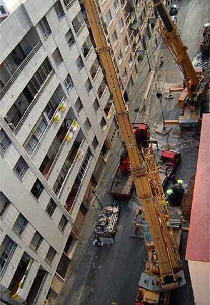 Las grúas levantan los vagones siniestrados a través de las perforaciones realizadas en la calle sobre el metro.