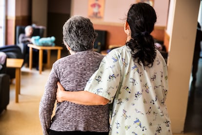 Una auxiliar ayuda a una mujer en una residencia de ancianos, en una foto de archivo.