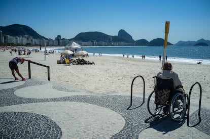 Una mujer en silla de ruedas, junto a las escaleras, mira la playa de Copacabana, en Río de Janeiro (Brasil).