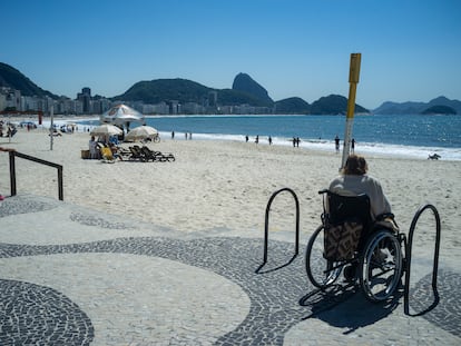 Una mujer en silla de ruedas, junto a las escaleras, mira la playa de Copacabana, en Río de Janeiro (Brasil).
