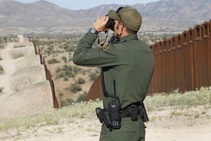 Un agente de la patrulla fronteriza vigila la valla en Nogales, por donde miles de personas tratan de cruzar de México a EE UU.