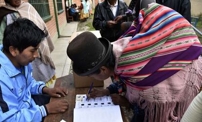 Una mujer indígena rellena sus datos personales, tras dejar su voto, en un colegio electoral en Huarina (Bolivia).