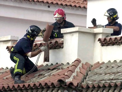 Tres bomberos retiran tejas arrancadas por la tormenta tropical Delta de un tejado de Tenerife.