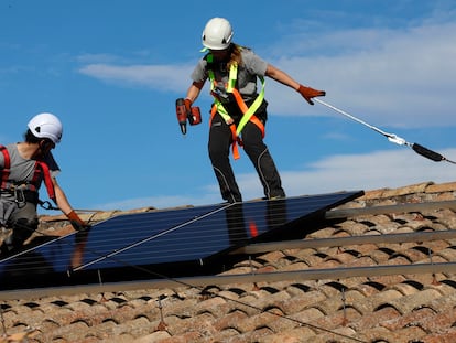 Dos trabajadores colocan placas solares en el tejado de una casa particular.