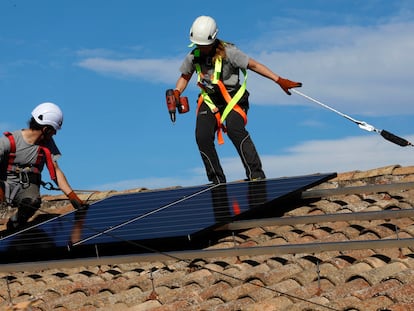 Dos operarios trabajan en la instalación de placas solares en el tejado de una casa, esta semana en Avinyó (Barcelona).