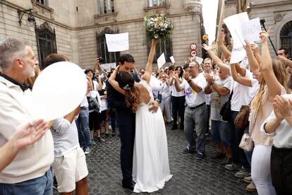 Unos recién casados se besan en la plaza de Sant Jaume de Barcelona mientras los manifestantes les aplauden.