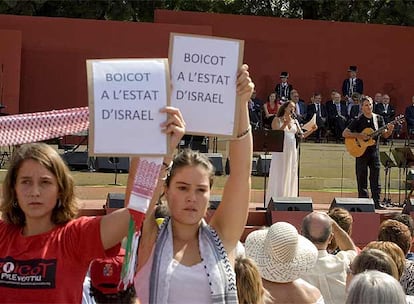 Dos jóvenes reclaman el boicoteo a Israel mientras Noa, al fondo, interpreta  <i>El Cant del ocells</i>.