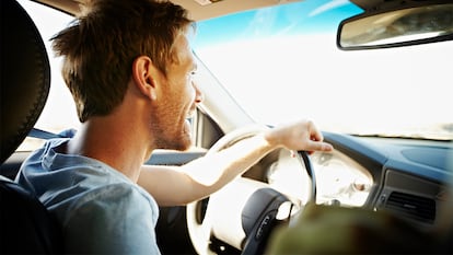 Un hombre conduciendo por la carretera soleada