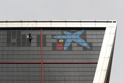 Un operario quita el último trozo de vinilo verde que escribía el logo de Bankia.