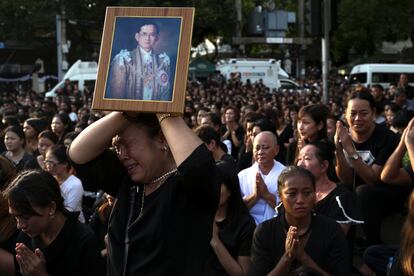 Una mujer llora sosteniendo un retrato del rey tailandés Bhumibol Adulyadej mientras trasladan su cuerpo desde el hospital de Bangkok (Tailandia), el 14 de octubre de 2016.