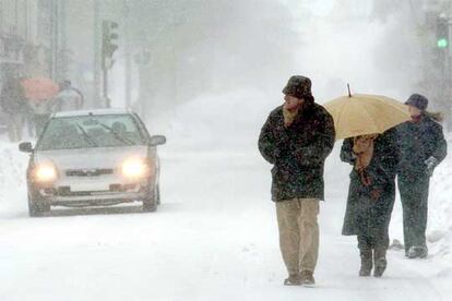 Un grupo de personas camina por la avenida principal de la localidad cntabra de Reinosa, completamente cubierta por la nieve.