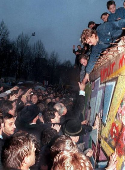 El canciller alemán Helmut Kohl estrecha la mano de un ciudadano berlinés  encaramado en lo alto del Muro de Berlín, cerca de la Puerta de Brandenburgo, el 22 de diciembre de 1989.
Foto: EFE