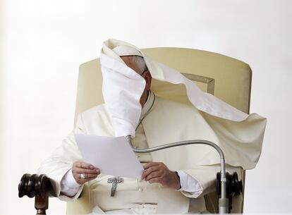 El manto Papa Francisco se levanta por el viento mientras éste lee su mensaje durante la audiencia general en la Plaza de San Pedro, en el Vaticano.