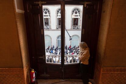 Una mujer sigue desde una ventana del Parlament la intervención del candidato de ERC a la presidencia de la Generalitat, Pere Aragonès.