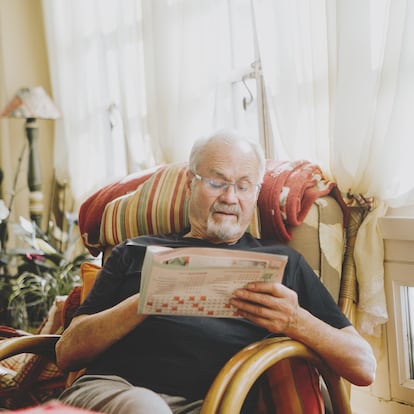 senior man doing crossword on newspaper