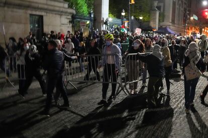 Unos manifestantes cargan barricadas mientras la policía intenta acordonar el campus.