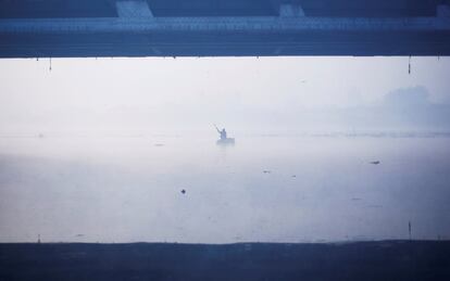 Un hombre navega en un bote hecho a mano a través del río Yamuna, en Nueva Delhi (India).